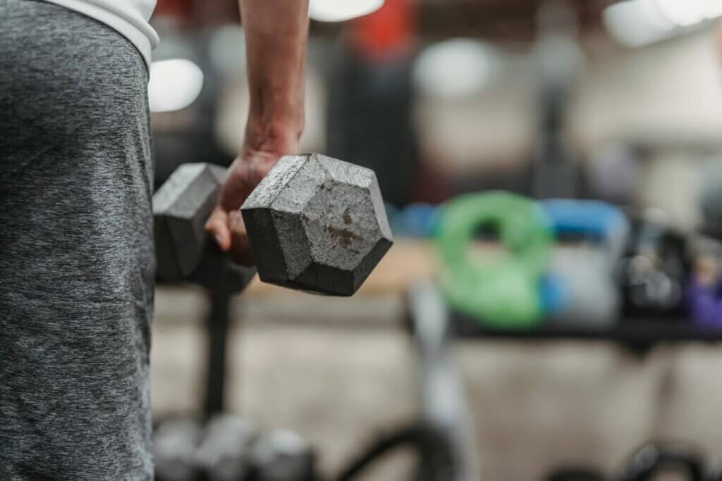 Ethnic sportsman training with dumbbells in gym